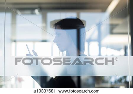 Side view through window of young woman holding digital tablet View Large Photo Image Stock Image - Side view through window of young woman holding digital tablet. Fotosearch