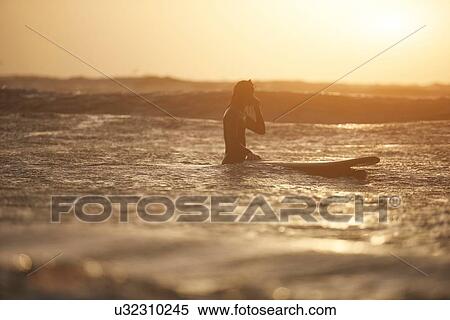 Stock Photography - Silhouette of young male surfer and surfboard in sea, Devon, England, UK. Fotosearch
