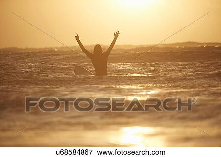 Silhouette of young male surfer with arms raised at sea, Devon, England, UK View Large Photo Image Stock Photo - Silhouette of young male surfer with arms raised at sea, Devon, England, UK. Fotosearch