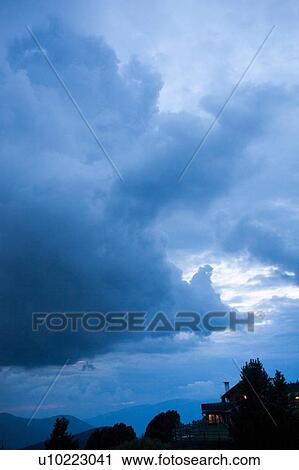 Stock Image - Silhouetted landscape and storm clouds at dusk, Brixen, Dolomites, Austria. Fotosearch