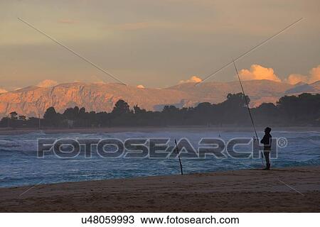 Silhouetted man fishing from beach at sunset, Macari, San Vito Lo Capo, Sicily, Italy View Large Photo Image Stock Image - Silhouetted man fishing from beach at sunset, Macari, San Vito Lo Capo, Sicily, Italy. Fotosearch
