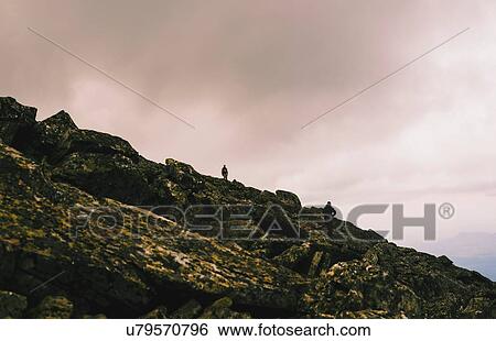 Stock Photograph - Silhouetted view of two men hiking on rugged rocks, Ural Mountains, Russia. Fotosearch