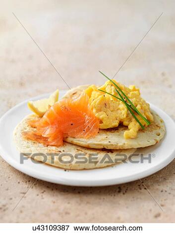 Stock Photo - Smoked salmon and scrambled egg on blini with chive garnish. Fotosearch