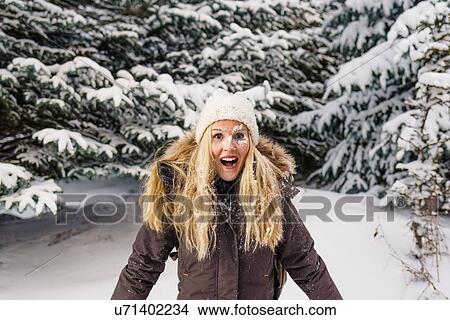 Picture - Snow covered mid adult woman looking at camera, mouth open in surprise smiling. Fotosearch