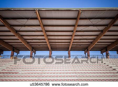 Stock Photograph - Sport stadium seating with tin roof against blue sky. Fotosearch