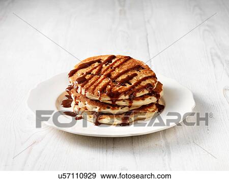 Stock Photo - Stack of chocolate chip pancakes drizzled with chocolate sauce. Fotosearch