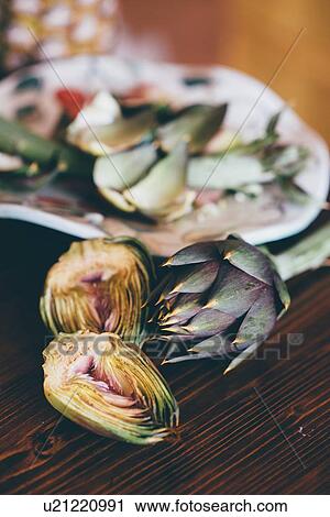 Stock Image - Still life of prepared globe artichoke on kitchen table. Fotosearch