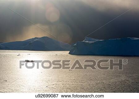 Storm clouds and sunlight over icebergs in Ilulissat icefjord, Disko Bay, Greenland View Large Photo Image Stock Photo - Storm clouds and sunlight over icebergs in Ilulissat icefjord, Disko Bay, Greenland. Fotosearch