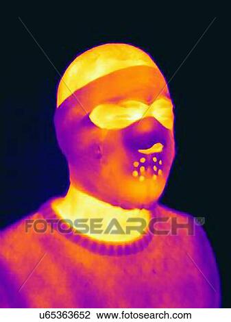 Stock Image - Thermal image of man wearing threatening head mask. Fotosearch