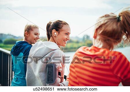 Three female runners chatting on city footbridge View Large Photo Image Stock Image - Three female runners chatting on city footbridge. Fotosearch