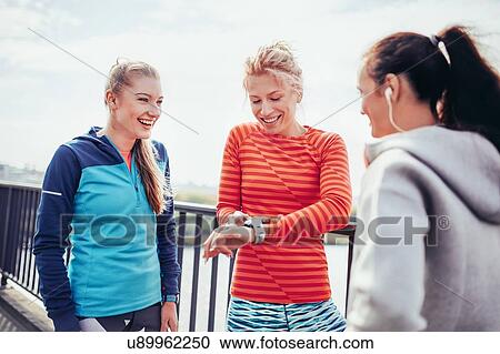 Three female runners coordinating time on city footbridge View Large Photo Image Stock Image - Three female runners coordinating time on city footbridge. Fotosearch