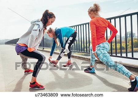 Three female runners doing warm up exercise on footbridge View Large Photo Image Stock Photo - Three female runners doing warm up exercise on footbridge. Fotosearch