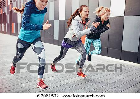 Stock Image - Three female runners racing up from underpass. Fotosearch