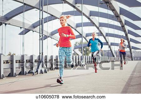Three female runners running across city footbridge View Large Photo Image Stock Photo - Three female runners running across city footbridge. Fotosearch