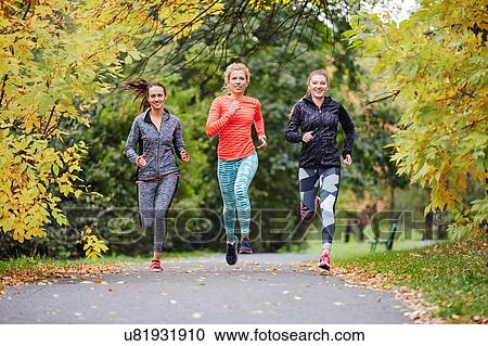 Stock Image - Three female runners running along park path. Fotosearch