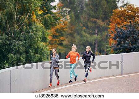 Stock Photograph - Three female runners running along park road. Fotosearch