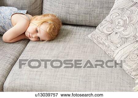 Tired female toddler lying on sofa View Large Photo Image Stock Photo - Tired female toddler lying on sofa. Fotosearch