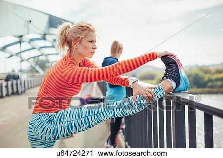 Two female runners doing warm up exercise on footbridge View Large Photo Image Stock Image - Two female runners doing warm up exercise on footbridge. Fotosearch