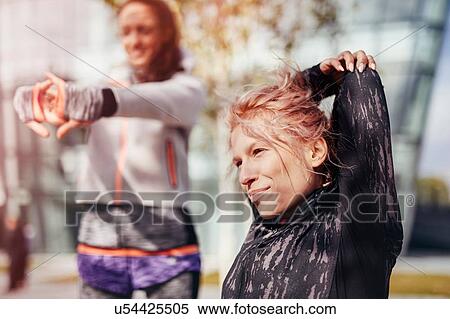 Stock Photography - Two female runners stretching arms in city. Fotosearch