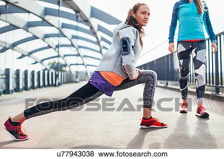 Two female runners warming up on city footbridge View Large Photo Image Stock Photo - Two female runners warming up on city footbridge. Fotosearch