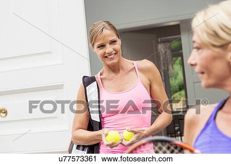 Stock Image - Two mature women preparing for game of tennis. Fotosearch