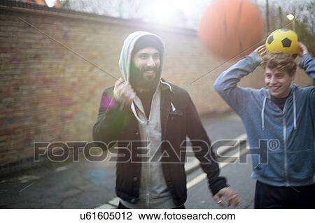 Two men walking in street, holding football View Large Photo Image Stock Image - Two men walking in street, holding football. Fotosearch