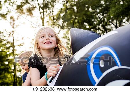 Stock Photo - Two sisters playing on inflatable whale in park. Fotosearch