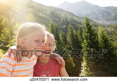 Two young girls laughing together, outdoors View Large Photo Image Stock Image - Two young girls laughing together, outdoors. Fotosearch