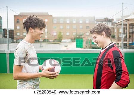 Two young men playing football on urban football pitch View Large Photo Image Stock Image - Two young men playing football on urban football pitch. Fotosearch