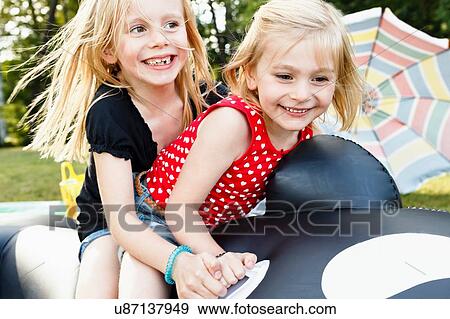 Two young sisters sitting on inflatable whale in park View Large Photo Image Stock Photo - Two young sisters sitting on inflatable whale in park. Fotosearch
