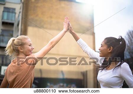 Two young women giving high five, outdoors View Large Photo Image Stock Image - Two young women giving high five, outdoors. Fotosearch
