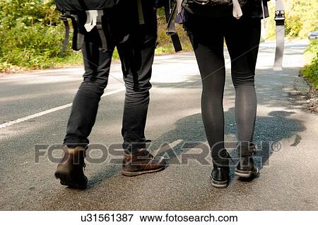 Waist down rear view of young hiking couple on rural road View Large Photo Image Stock Photo - Waist down rear view of young hiking couple on rural road. Fotosearch