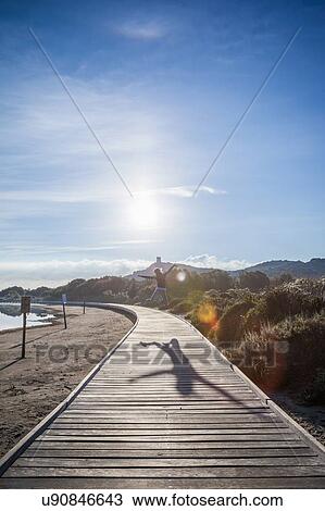 Woman jumping mid air over beach boardwalk, Villasimius, Sardinia, Italy View Large Photo Image Stock Image - Woman jumping mid air over beach boardwalk, Villasimius, Sardinia, Italy. Fotosearch