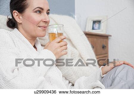 Stock Photograph - Woman relaxing at home, having a drink. Fotosearch