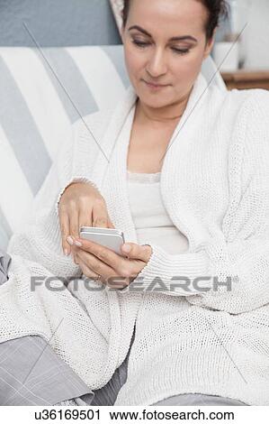 Woman relaxing at home, using smartphone View Large Photo Image Stock Image - Woman relaxing at home, using smartphone. Fotosearch