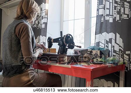 Woman using vintage sewing machine at table in front of window View Large Photo Image Stock Image - Woman using vintage sewing machine at table in front of window. Fotosearch