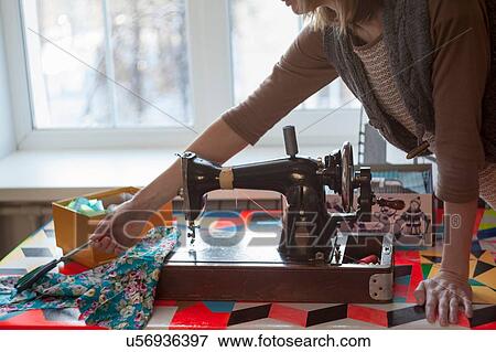 Woman with vintage sewing machine reaching for scissors at table View Large Photo Image Stock Photo - Woman with vintage sewing machine reaching for scissors at table. Fotosearch