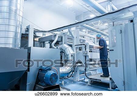Worker operating printing machine in food packaging printing factory View Large Photo Image Stock Photo - Worker operating printing machine in food packaging printing factory. Fotosearch