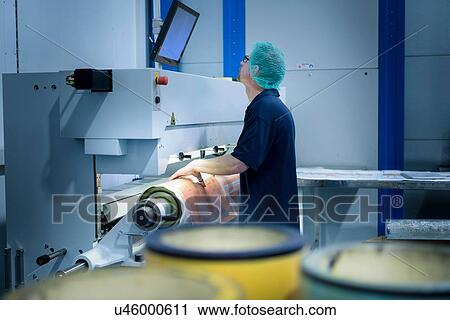 Stock Image - Worker preparing printing plates in food packaging printing factory. Fotosearch