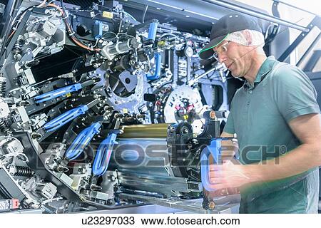 Stock Image - Worker with ink jet printer in food packaging printing factory. Fotosearch