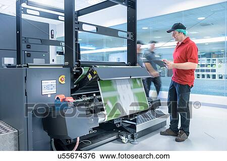 Stock Photograph - Worker with ink jet printer in food packaging printing factory. Fotosearch
