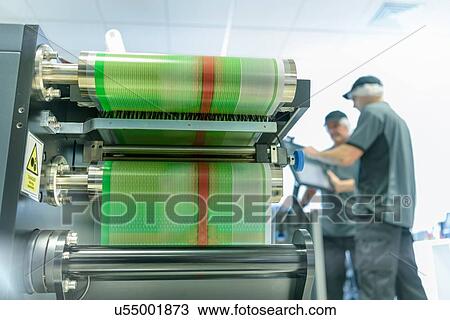 Stock Image - Workers with ink jet printer in food packaging printing factory. Fotosearch