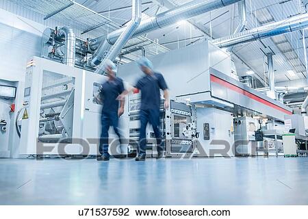 Stock Image - Workers with printing machine in food packaging printing factory. Fotosearch