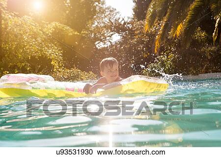 Young boy in swimming pool, holding onto inflatable View Large Photo Image Stock Image - Young boy in swimming pool, holding onto inflatable. Fotosearch