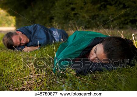 Young couple asleep in sleeping bags in field View Large Photo Image Stock Photo - Young couple asleep in sleeping bags in field. Fotosearch