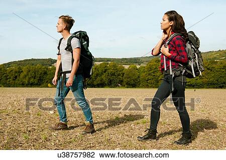 Young couple hiking across in field, Great Missenden, Buckinghamshire, U. K View Large Photo Image Stock Image - Young couple hiking across in field, Great Missenden, Buckinghamshire, U. K. Fotosearch