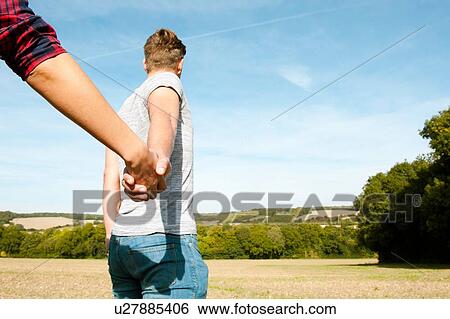 Stock Photograph - Young couple holding hands in field landscape, Great Missenden, Buckinghamshire, U. K. Fotosearch