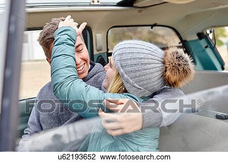 Stock Image - Young couple in front seat of car at beach. Fotosearch