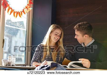 Young couple on date in cafe reading magazine View Large Photo Image Stock Image - Young couple on date in cafe reading magazine. Fotosearch