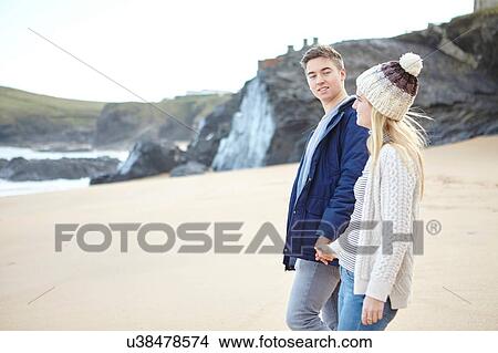 Young couple strolling hand in hand on beach, Constantine Bay, Cornwall, UK View Large Photo Image Picture - Young couple strolling hand in hand on beach, Constantine Bay, Cornwall, UK. Fotosearch